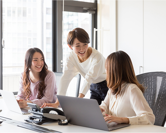 Multiple smiling employees working around a laptop, promoting flexible work practices